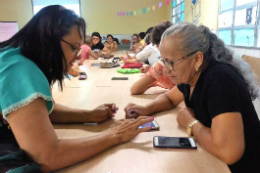 Imagem: foto de senhoras sentadas à mesa olhando celulares