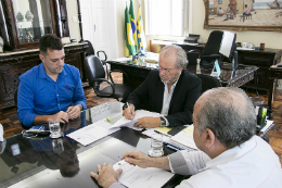 Imagem: foto de homens sentados à mesa assinando um papel