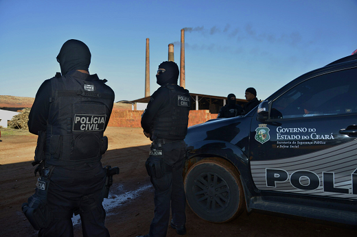 Imagem: Dois policiais civis do Ceará de costas, ao lado de uma viatura (Foto: Governo do Estado do Ceará)