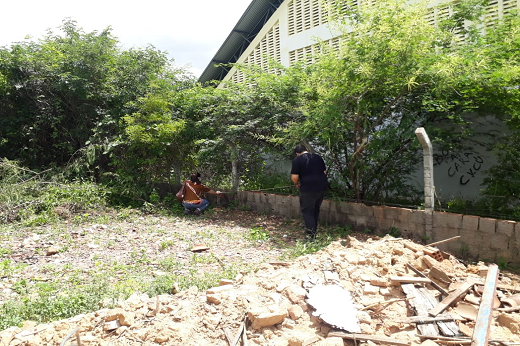 Terreno com restos de construção; ao fundo, integrantes do PROHABITA fazem medição do terreno (Foto: Divulgação/PROHABITA)