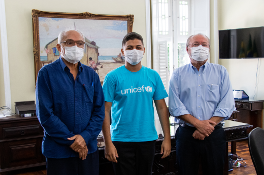 Foto do estudante Felipe Caetano ladeado pelo vice-reitor Glauco Lobo e pelo reitor Cândido Albuquerque