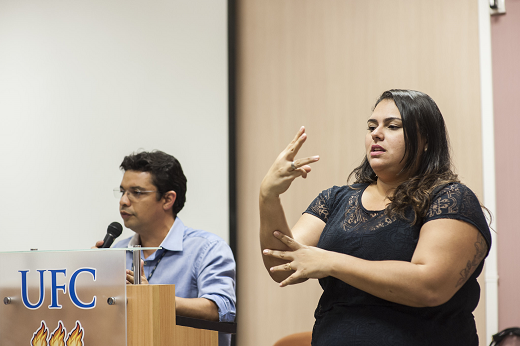 Davi Cândido, técnico em Assuntos Educacionais, e Graziele Gomes, diretora da Divisão de Tradução e Interpretação Libras/português, ambos da Secretaria de Acessibilidade, durante interpretação de Libras/português em evento da comunidade acadêmica (Foto: Viktor Braga/UFC)