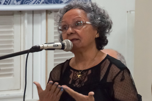 Imagem: foto da maestrina Izaíra Silvino falando em frente ao microfone