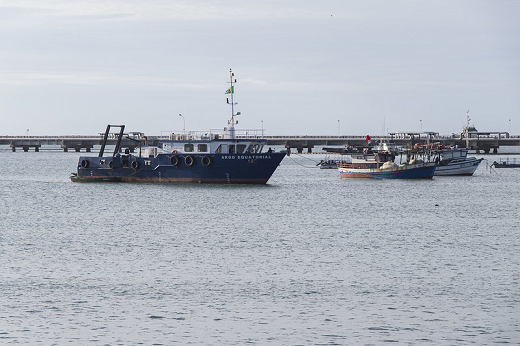Imagem: foto de dois barcos atracados no mar. Ao fundo, é possível ver um pier no mar