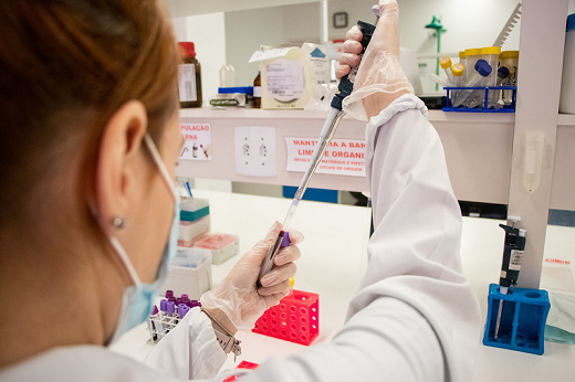Imagem: foto de uma jovem de máscara em um laboratório fazendo experimentos