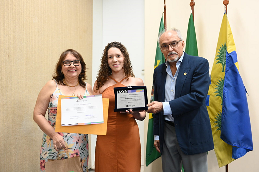 Imagem: A pró-reitora de Graduação, Profª Ana Paula de Medeiros ao lado de uma das estudantes premiadas e do vice-reitor, Prof. Glauco Lobo (Foto: Viktor Braga/UFC)