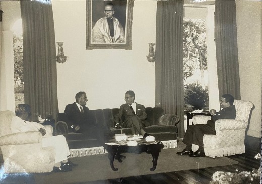 Imagem: foto em preto e branco de três homens sentados em sofás e poltronas em um salão. Pelas características da foto, é possível notar que ela é antiga