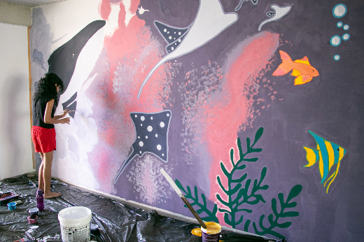 Imagem: estudante pintando painel na residência universitária 