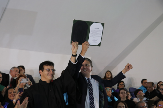 Imagem: Foto do reitor Custódio Almeida e ministro Camilo Santana erguendo o termo de posse