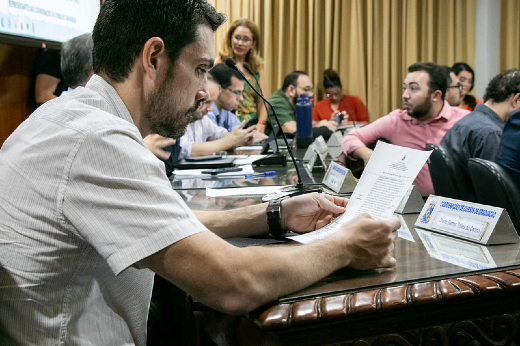 Imagem: Foto de um dos conselheiros do CEPE segurando um papel para ler o conteúdo de um dos processos em votação pelo conselho