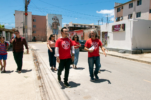 Imagem: Foto do reitor Custódio Almeida, vestido com a blusa do MTST, caminhano na comunidade do Residencial José Euclides, no Jangurussu