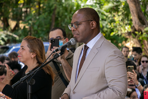 Imagem: Foto do ministro Silvio Almeida, de terno e gravata, discursando no palco dos Encontros Universitários e ao lado uma intérprete de Libras