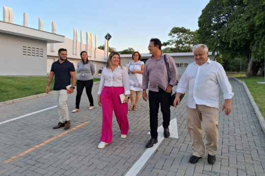 Imagem: Foto do reitor Custódio Almeida e da equipe da FIOCRUZ andando ao ar livre em uma estrada pavimentada com pisos de concreto intertravado
