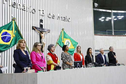Imagem: Foto das pesquisadoras homenageadas no Dia das Mulheres na Ciência em pé na mesa do plenário da Assembleia Legislativa