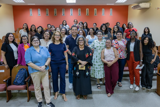 Imagem: Grupo de pessoas em pé no auditório posa para foto