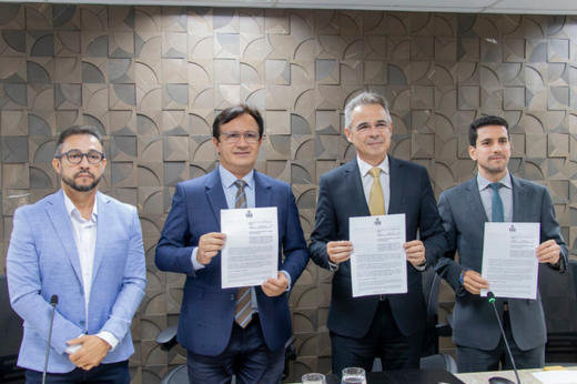 Quatro homens reunidos segurando o papel do protocolo de intenções assinado