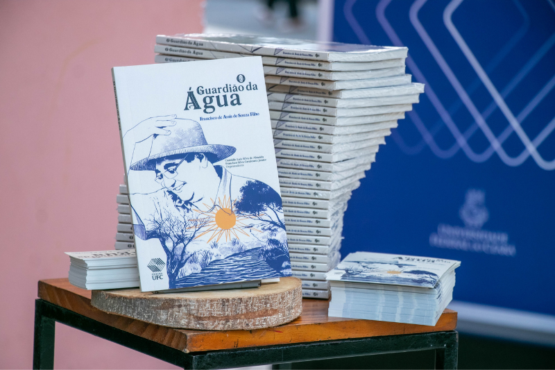 A data de lançamento do livro foi escolhida por coincidir com o 60º aniversário do engenheiro civil e professor Francisco de Assis de Souza Filho, falecido em março deste ano (Foto: Gladson Caldas/UFC) Imagem: Foto de exemplares empilhados do livro "O Guardião da Água" no estande da Editora UFC