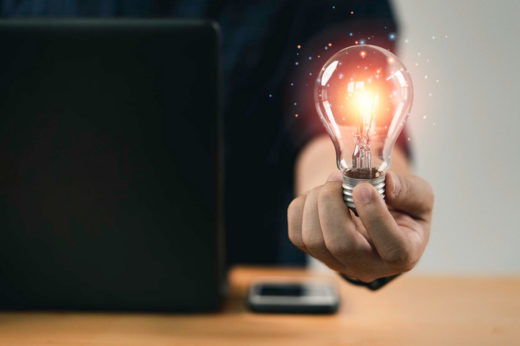 Mão de uma pessoa segurando lâmpada com luz brilhante indicando pensamento criativo