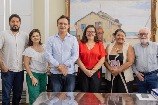 Pessoas reunidas atrás da mesa do reitor, posando para a foto