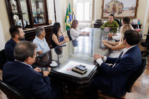 Pessoas sentadas na mesa da Reitoria em reunião com o reitor