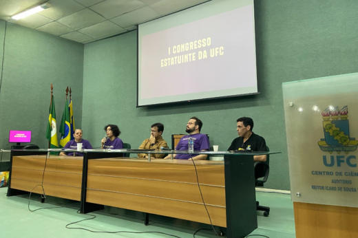 Delegados e delegadas dos segmentos docente, técnico-administrativo e discente se reuniram para seguir os processos de elaboração da minuta do novo Estatuto da UFC (Foto: Divulgação) Imagem: Foto da mesa de abertura e o estudante Florindo da Rocha utilizando o microfone