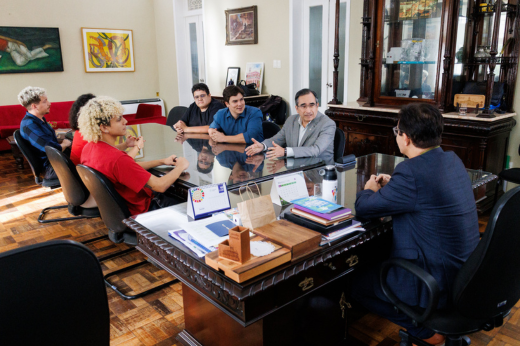 Imagem: Foto da mesa de reunião com os participantes sentados e o reitor Custódio Almeida na ponta da mesa