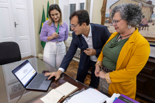 Os certames tiveram 22 mil inscritos no concurso de técnicos e mais de 1 mil concorrentes no do magistério superior (Foto: Gutierrez Reges / UFC) Imagem: Foto em que o reitor Custódio Almeida utiliza um computador para publicar o resultado final, estando acompanhado da vice-reitora Diana Azevedo e da presidente da CCV, Luana Sombra