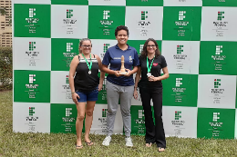 Imagem: Foto de três mulheres em pé, sendo duas com melhadas no peito e a do meio segurando um troféu