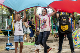 Imagem: foto de duas meninas balançando um grande pedaço de tecido nos Jardins da Reitoria