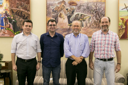 Imagem: foto de quatro homens brancos com roupas sociais em pé sorrindo para a foto