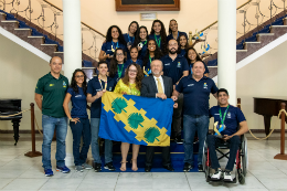 Foto do reitor Cândido Albuquerque com os estudantes-atletas da UFC na escada do Salão Nobre da Reitoria