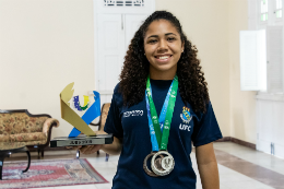 Foto da atleta Marieta Sales segurando um troféu e com duas medalhas no peito