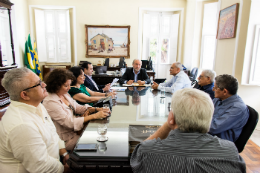 Mesa do Gabinete do reitor com várias pessoas sentadas representantes da UFC e do Instituto Myra Eliane