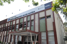 Imagem: foto da fachada de um prédio branco com o nome Hospital Universitário Walter Cantídio na cor preta