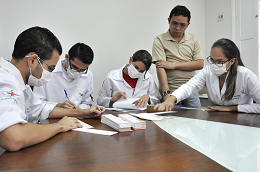 Imagem: fotos de pessoas de jaleco branco sentadas em uma mesa de reunião