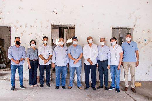 Imagem: Comitiva formada por administração superior, Prefeitura de Maracanaú e setores produtivos posa em frente a galpão industrial.