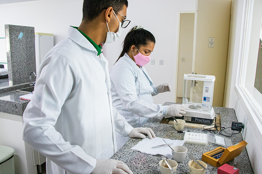 Pesquisadores utilizando equipamento no balcão do laboratório