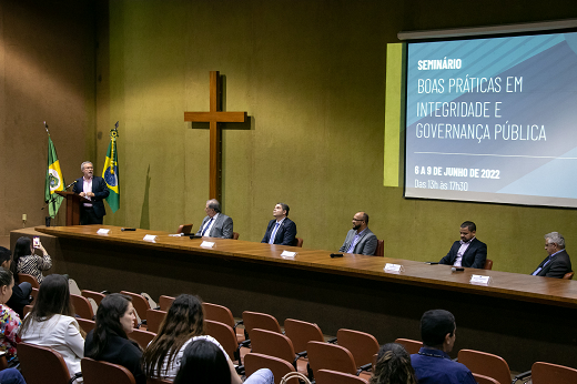 Imagem: Reitor Cândido Albuquerque fala na tribuna do auditório da CGU. Ao fundo, projeção mostra o tema do seminário, "Boas Práticas em integridade e Governança Pública". (Foto: Viktor Braga/UFC Informa)