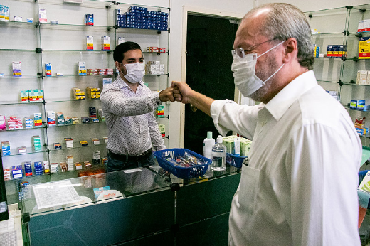 Imagem: reitor cumprimenta servidor da Farmácia-Escola durante visita ao equipamento