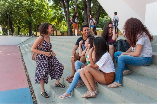 Imagem: estudantes sentados na escada da Concha Acústica da UFC, na Reitoria, em foto antes da pandemia