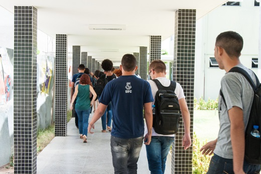 Imagem: Foto de estudantes, de costas, caminhando em grupo em um corredor no Campus do Pici (Foto: Viktor Braga/UFC)