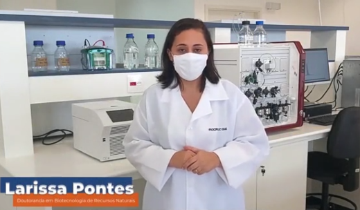 A pesquisadora Larissa Pontes usando máscara e jaleco, em ambiente de laboratório