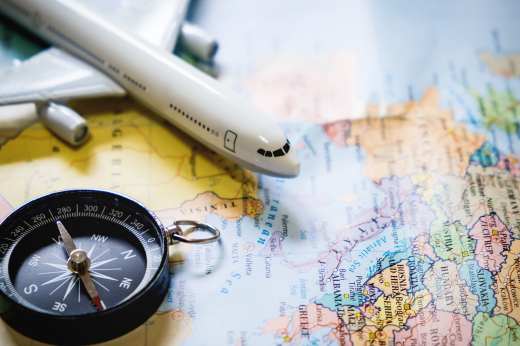 Imagem: Miniatura de avião e bússola sobre mapa-mundi