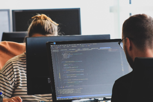 Imagem: Dois jovens de frente para o computador atuando em programação 