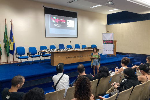 Imagem: mulher fala em auditório da Reitoria