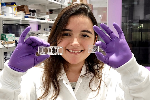 Imagem: A doutoranda Maria Elisa Quezado Lima Verde com as plataformas de organs on-a-chip; a do lado direito foi desenvolvida durante o projeto da pesquisadora (Foto: Arquivo pessoal)