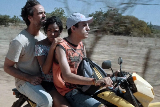 Imagem: três homens sentados em uma moto amarela durante cena do filme "Represa"