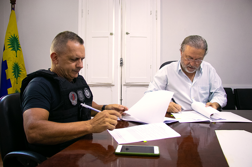 Imagem: Secretário Mauro Albuquerque (Administração Penitenciária) e reitor Cândido Albuquerque (UFC) assinam termo de cooperação; convênio será focado na qualidade de vida de policiais penais. (Foto: Gutiérrez Reges/ UFC Informa)