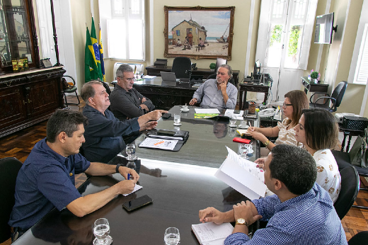 Imagem: homens e mulheres conversando em torno de uma mesa no gabinete do reitor