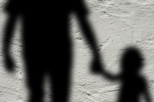 Imagem: Sombras na parede de criança de mãos dadas com adulto
